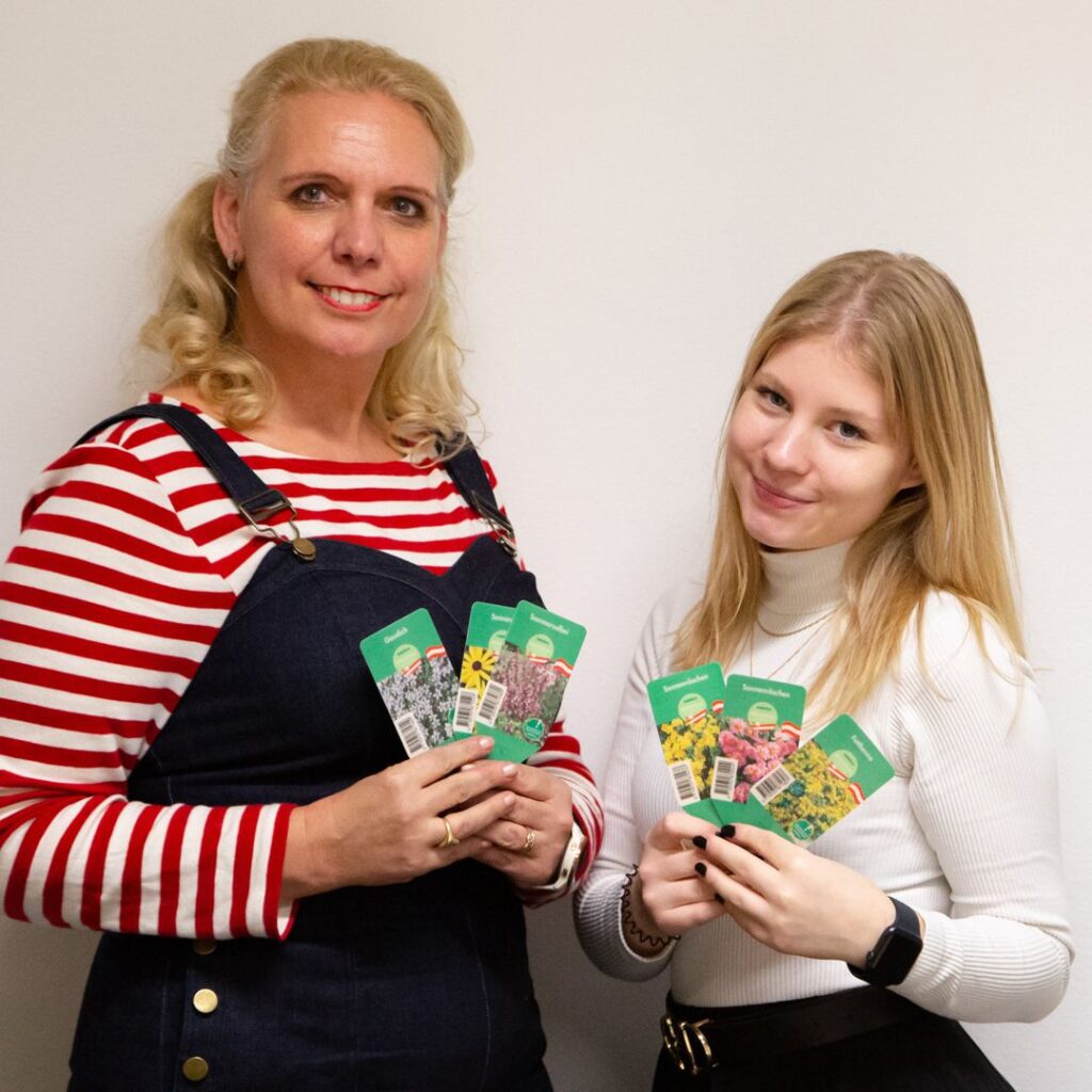 Ute Zimmermann and Lizzy showing plant labels printed on the biopolymer paper.